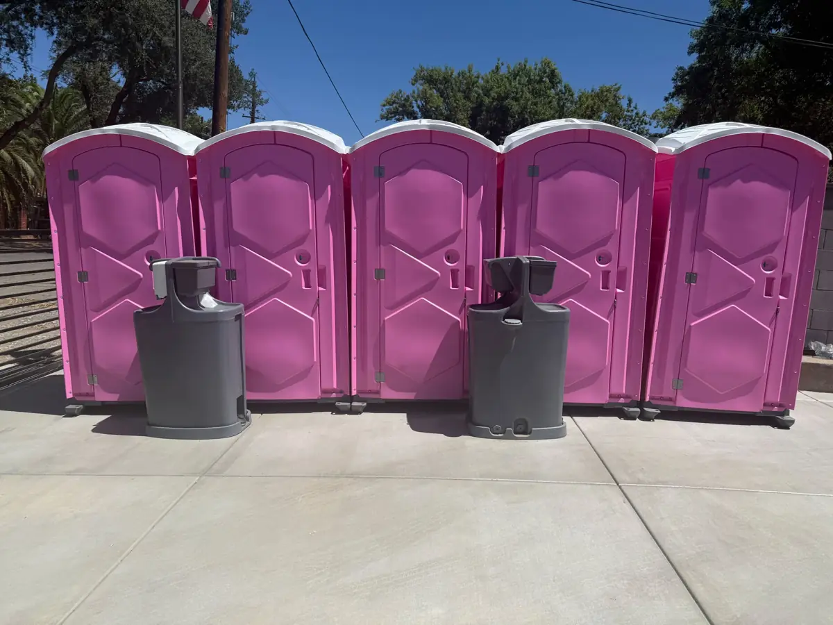 Row of pink portable toilets with two hand-wash stations set up for an event
